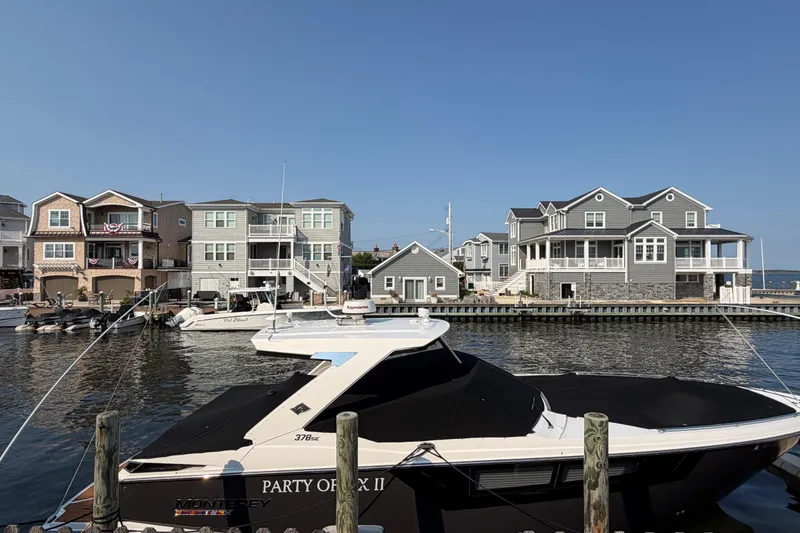 The Image of 2017 Monterey 378SE Super Express boat docked near waterfront homes under clear blue sky. - 1
