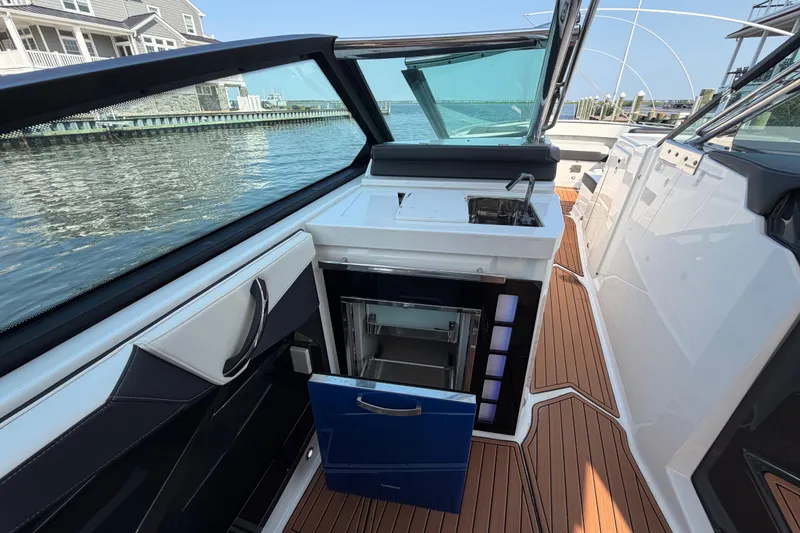 Slide: The Image of 2017 Monterey 378SE Super Express boat interior with kitchenette and open fridge by the water. - 17