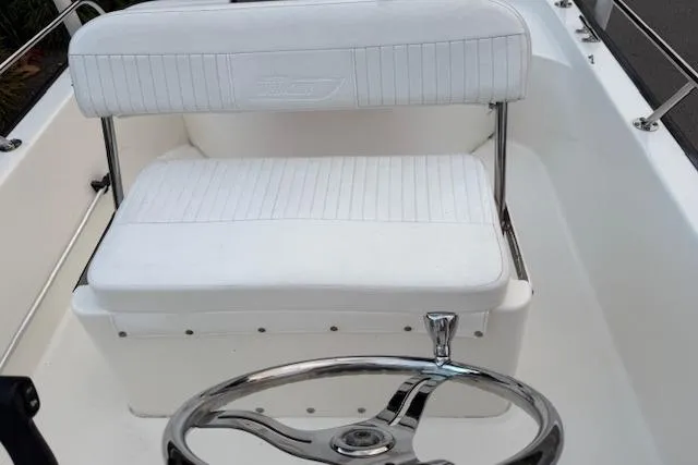Slide: The Image of 2016 Boston Whaler 150 Montauk boat interior with white seating and steering wheel. - 22