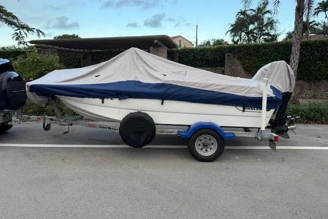 Slide: The Image of 2016 Boston Whaler 150 Montauk boat covered on trailer, parked on street. - 3