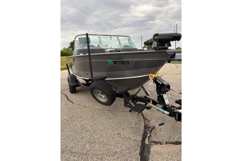 Slide: The Image of 2018 Lund 1775 Impact XS boat on trailer, parked on pavement under cloudy sky. - 3