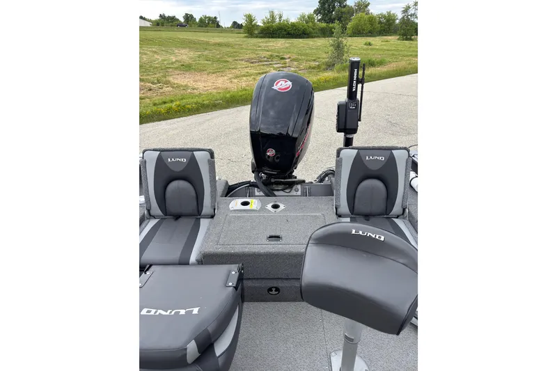 Slide: The Image of 2018 Lund 1775 Impact XS boat interior with seating and motor, parked on a road. - 6