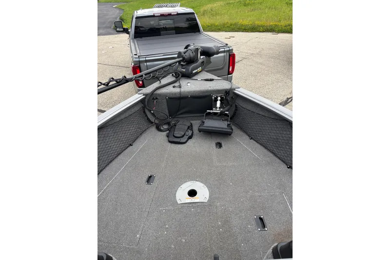 Slide: The Image of 2018 Lund 1775 Impact XS boat interior with fishing equipment and truck in background. - 9