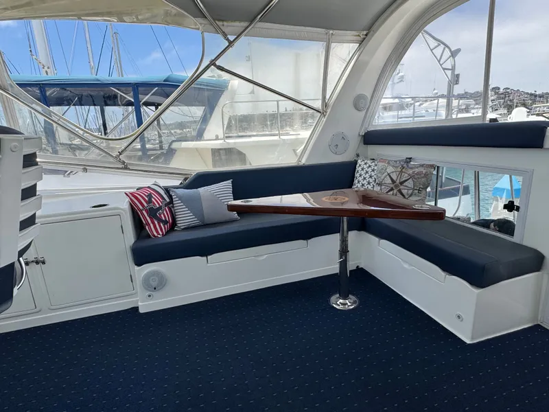 Slide: The Image of Interior of a yacht with blue seating and a wooden table, surrounded by windows. - 20