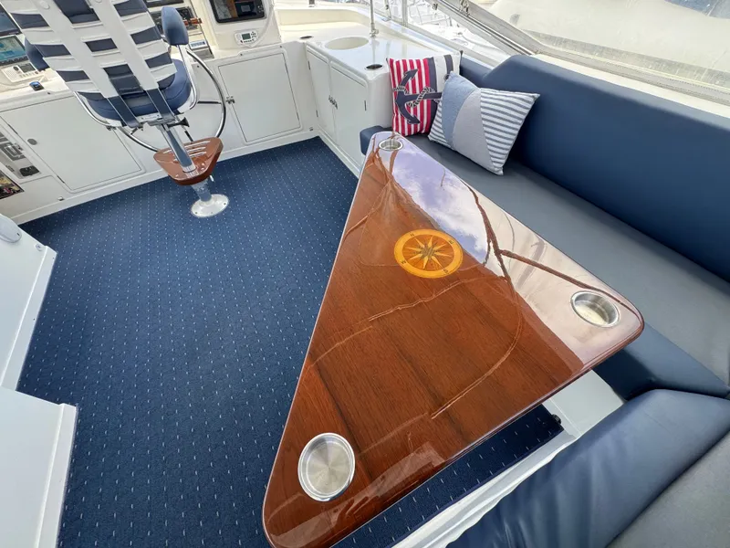 Slide: The Image of Interior of a yacht with a triangular wooden table and blue cushions. - 25