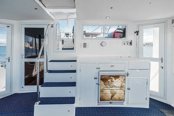 Slide: The Image of Yacht interior with blue carpets, white walls, stairs, and a world map. - 27