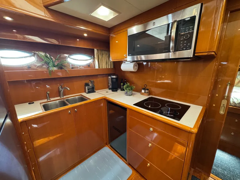 Slide: The Image of A yacht kitchen with wood paneling, sink, stove, and microwave. - 38