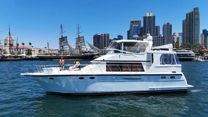 Slide: The Image of A white yacht with two people on board sails in front of a city with tall buildings. - 5