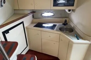 Slide: The Image of 2002 Cruisers Yachts 3372 Express cabin kitchen with stove, sink, and storage cabinets. - 11