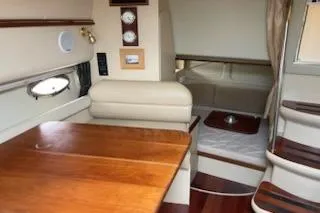 Slide: The Image of Interior of 2002 Cruisers Yachts 3372 Express, featuring wood table and cozy seating area. - 12