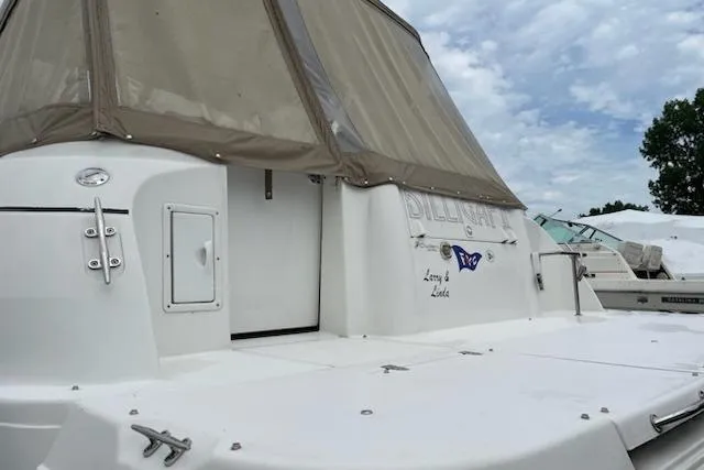Slide: The Image of 2002 Cruisers Yachts 3372 Express boat with beige canopy, docked under cloudy sky. - 3