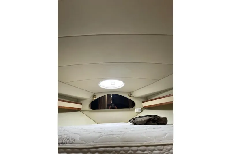 Slide: The Image of Interior cabin of 2002 Cruisers Yachts 3372 Express, featuring a cozy bed and porthole. - 9