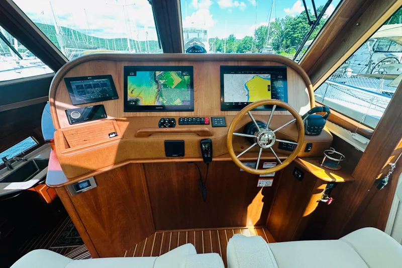 Slide: The Image of Helm of 2025 Sabre 48 Salon Express with navigation screens and wooden steering wheel. - 26