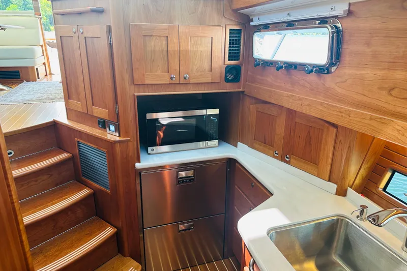 Slide: The Image of Interior of 2025 Sabre 48 Salon Express yacht kitchen with wood cabinetry and stainless steel appliances. - 39