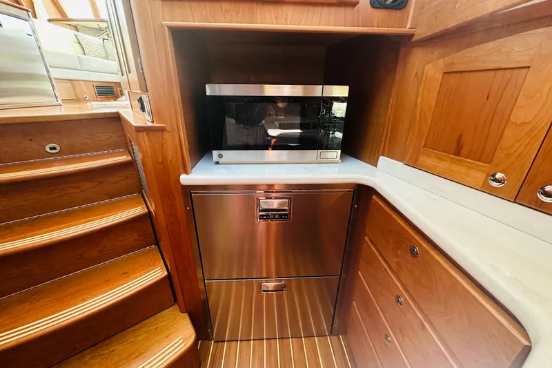 Slide: The Image of Modern kitchen area in 2025 Sabre 48 Salon Express yacht with microwave and wooden cabinetry. - 40