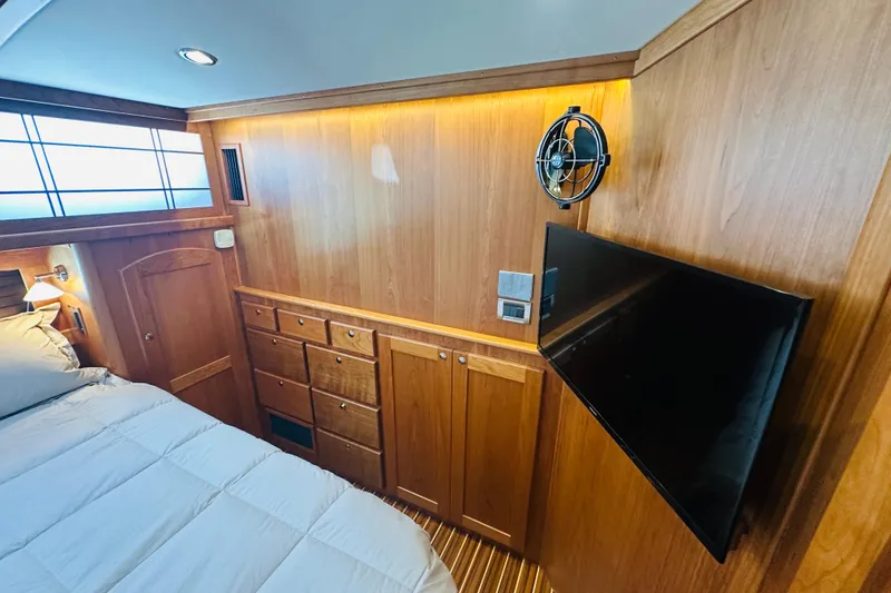 Slide: The Image of Bedroom interior of 2025 Sabre 48 Salon Express yacht with wood paneling and mounted TV. - 47