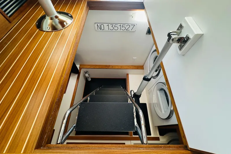 Slide: The Image of Staircase in 2025 Sabre 48 Salon Express yacht, featuring wood paneling and laundry area. - 59
