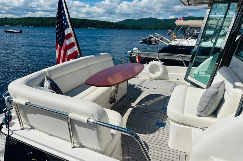 Slide: The Image of Luxurious 2025 Sabre 48 Salon Express yacht deck with seating, table, and scenic lake view. - 6