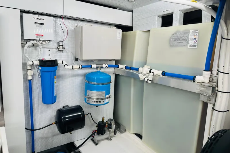 Slide: The Image of Engine room of 2025 Sabre 48 Salon Express, featuring water filtration and plumbing systems. - 73