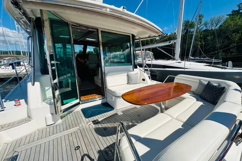 Slide: The Image of 2025 Sabre 48 Salon Express yacht with elegant outdoor seating and wooden table. - 8