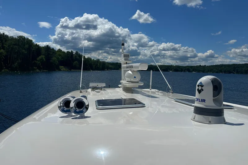 Slide: The Image of 2025 Sabre 48 Salon Express yacht on a serene lake under a partly cloudy sky. - 88