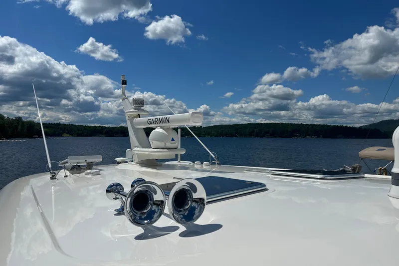 Slide: The Image of 2025 Sabre 48 Salon Express yacht with Garmin equipment on a serene lake under a cloudy sky. - 90