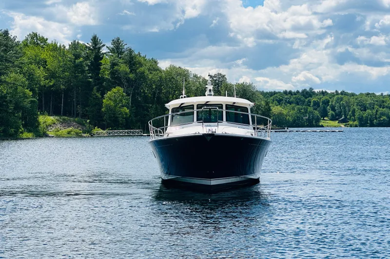 Slide: The Image of 2025 Sabre 48 Salon Express yacht cruising on a serene lake with lush forest backdrop. - 94