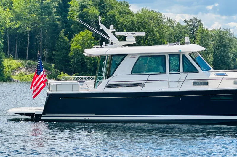 Slide: The Image of 2025 Sabre 48 Salon Express yacht on a serene lake with lush forest backdrop. - 95