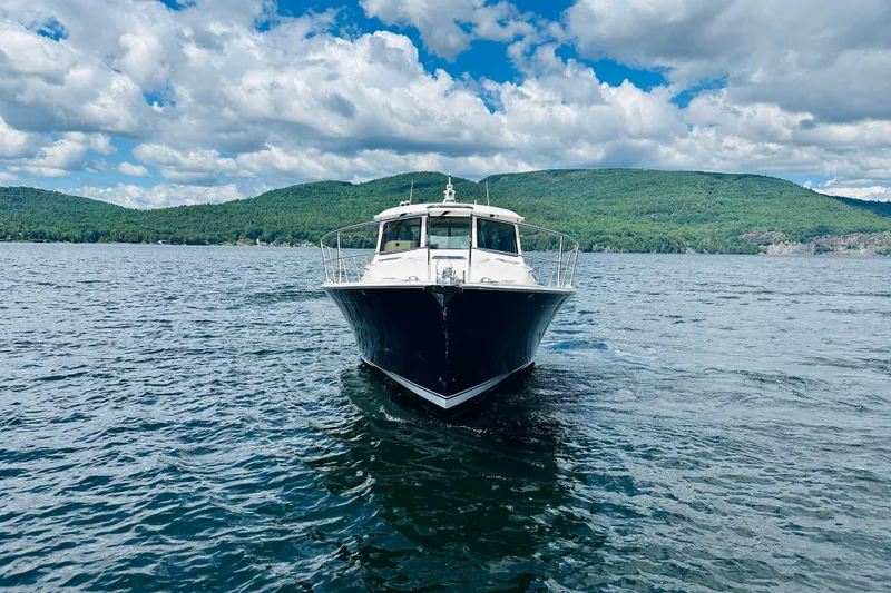 Slide: The Image of 2025 Sabre 48 Salon Express yacht cruising on a scenic lake with lush green hills. - 97
