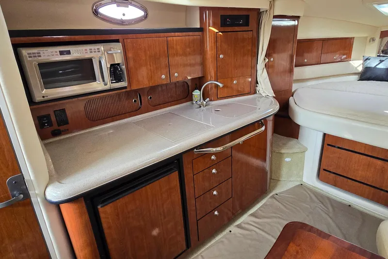 Slide: The Image of 2007 Sea Ray 340 Sundancer interior with kitchenette, featuring wood cabinetry and modern appliances. - 23
