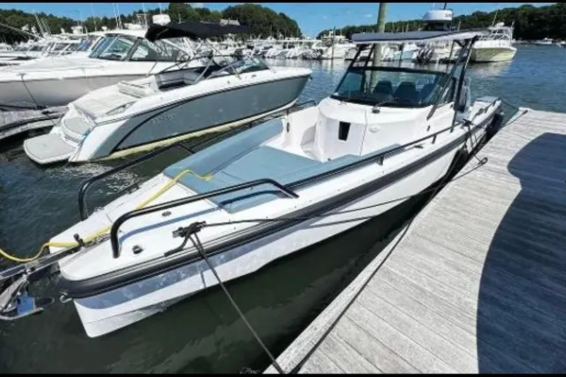The Image of 2022 Axopar 28 T-Top boat docked at a marina, surrounded by other vessels. - 1