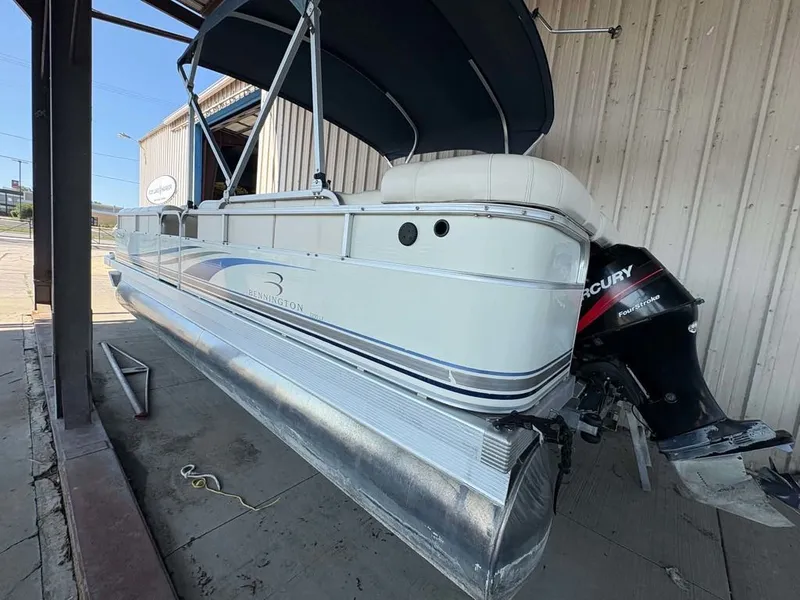 Slide: The Image of A 2002 Bennington 2250 LX pontoon boat with a Mercury outboard motor, parked in a covered area. - 7