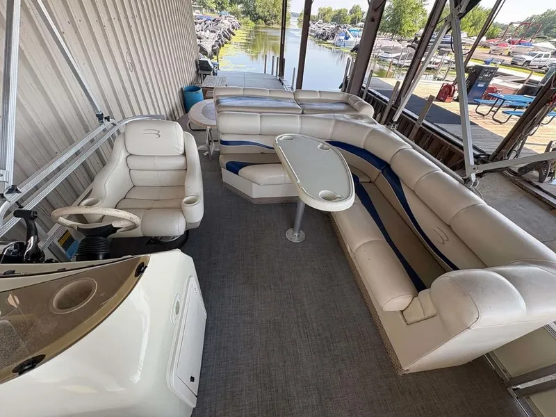 Slide: The Image of The image shows the interior of a 2002 Bennington 2250 LX pontoon boat with beige seating. - 6