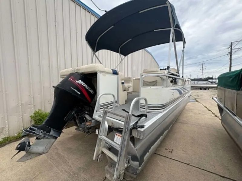 Slide: The Image of 2002 Bennington 2275 pontoon boat with outboard motor and canopy, parked on a concrete lot. - 7