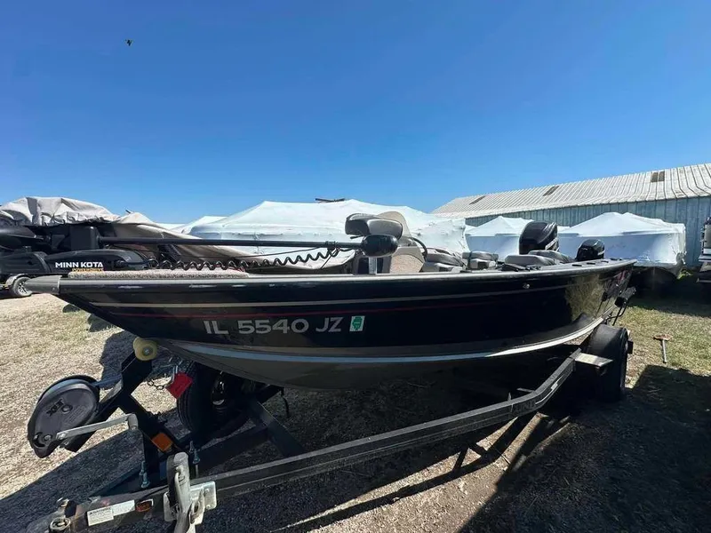 The Image of A black boat on a trailer, surrounded by white covers, under a clear blue sky. - 1