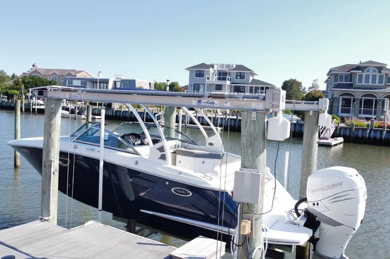 The Image of 2021 Cobalt 25SC boat docked at a marina with waterfront homes in the background. - 0