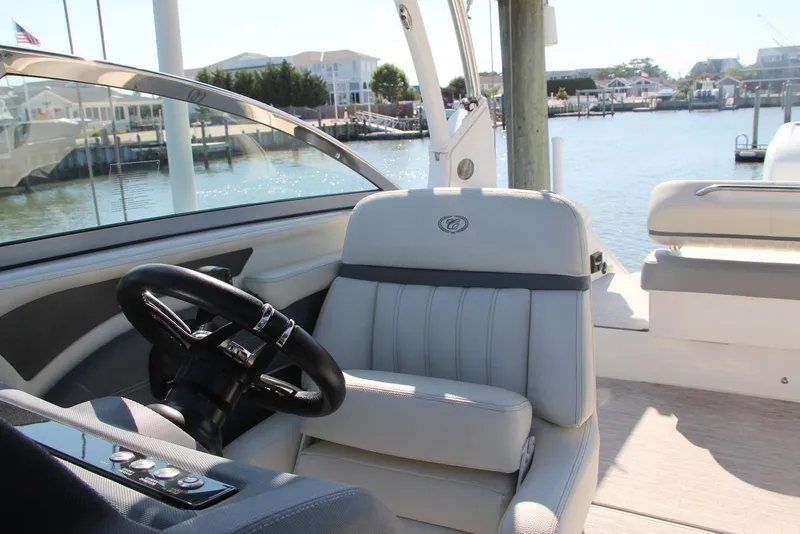 Slide: The Image of 2021 Cobalt 25SC boat interior with steering wheel and seating, docked by the waterfront. - 5