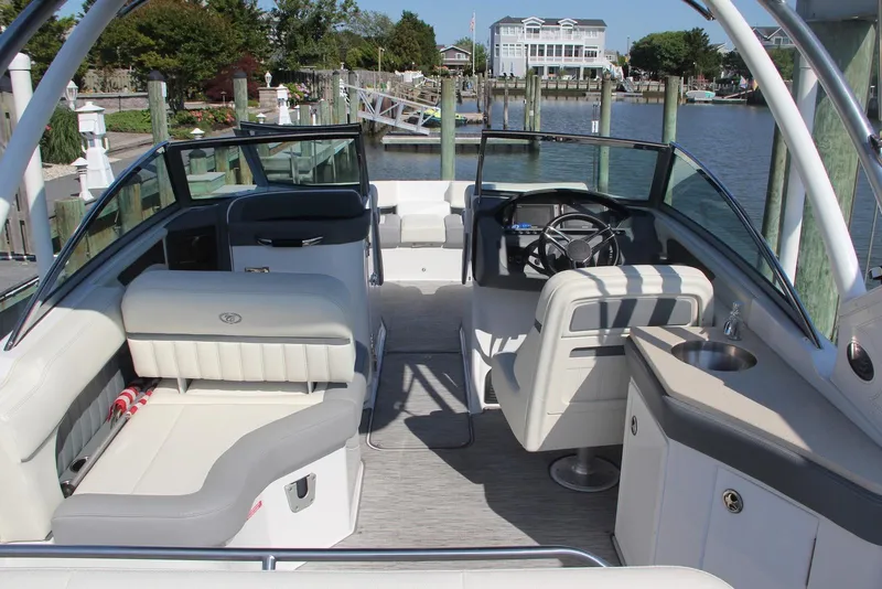Slide: The Image of 2021 Cobalt 25SC boat interior with seating, steering wheel, and sink at a dock. - 3