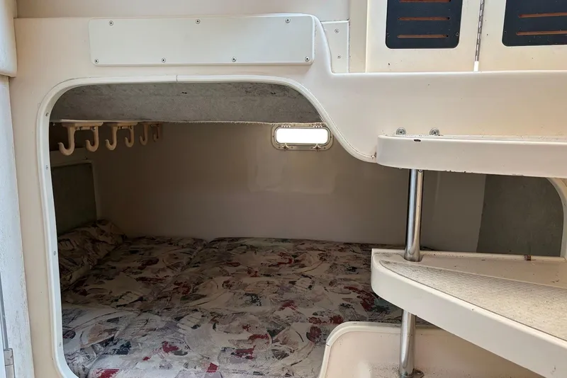 Slide: The Image of 1999 Grady-White Marlin 300 cabin interior with bed and storage hooks. - 10