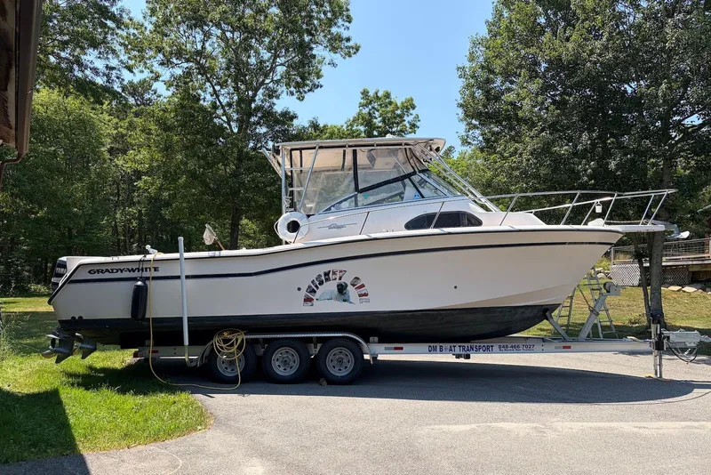 Slide: The Image of 1999 Grady-White Marlin 300 boat on trailer, parked outdoors with trees in background. - 1