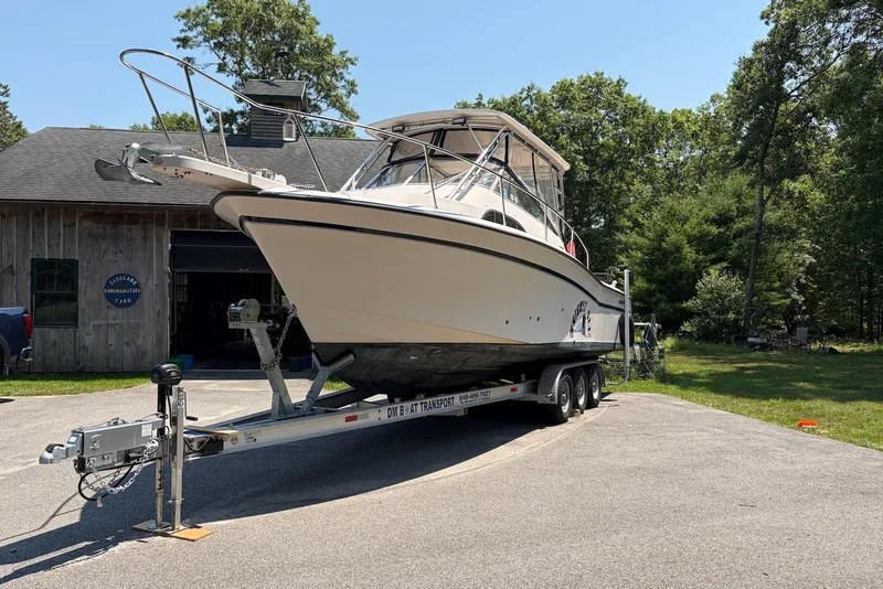 Slide: The Image of 1999 Grady-White Marlin 300 boat on trailer, parked outdoors near a wooden building. - 2