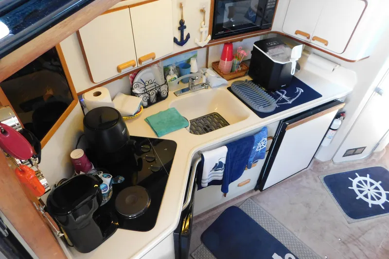 Slide: The Image of Compact kitchen in 1990 Sea Ray 350 Express Cruiser with nautical decor and modern appliances. - 27