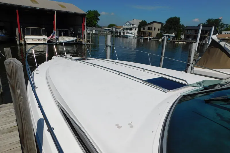 Slide: The Image of 1990 Sea Ray 350 Express Cruiser docked at a marina, surrounded by water and boats. - 3