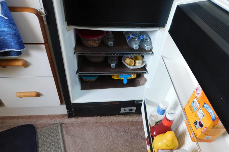 Slide: The Image of Mini fridge inside 1990 Sea Ray 350 Express Cruiser, stocked with drinks and condiments. - 52