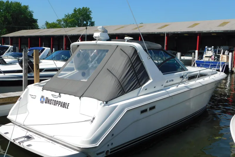 The Image of 1990 Sea Ray 350 Express Cruiser docked at marina, featuring "Unstoppable" on the stern. - 0
