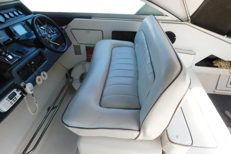 Slide: The Image of Interior of 1990 Sea Ray 350 Express Cruiser with helm and cushioned seating. - 10
