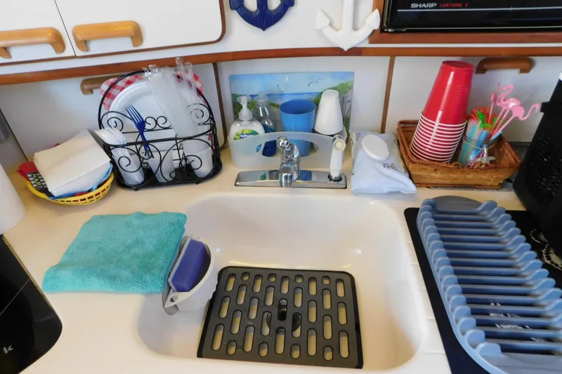 Slide: The Image of 1990 Sea Ray 350 Express Cruiser kitchen sink with utensils, cups, and cleaning supplies. - 55