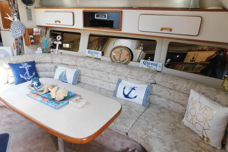 Slide: The Image of Interior of 1990 Sea Ray 350 Express Cruiser with nautical-themed decor and cozy seating. - 29