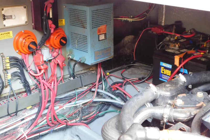 Slide: The Image of Engine compartment of a 1990 Sea Ray 350 Express Cruiser with wiring and battery setup. - 69