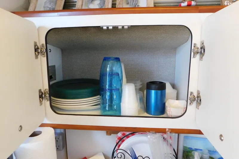 Slide: The Image of Cabinet in 1990 Sea Ray 350 Express Cruiser with plates, cups, and a thermos. - 57